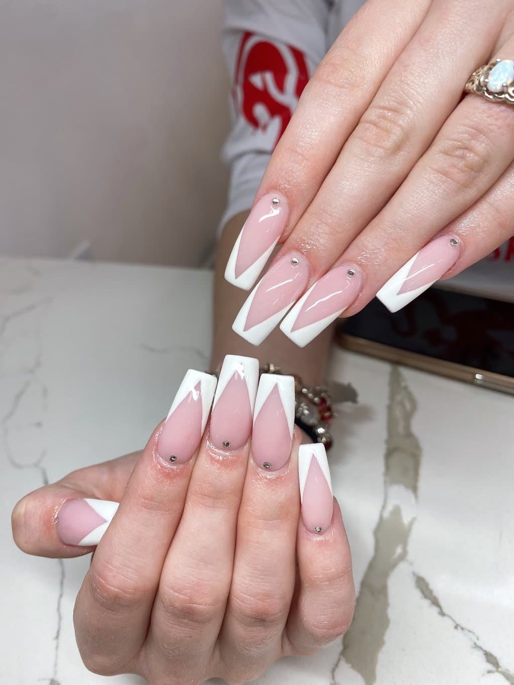 Nude nails with white V-shaped French tips and small crystals