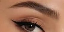Close-up of a softly arched, groomed eyebrow above a lined eye
